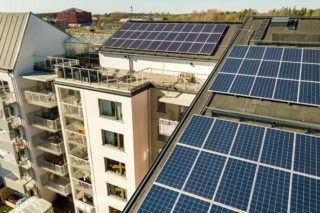 Aerial view of solar photovoltaic panels on a roof top of residential building block for producing clean electric energy. Autonomous housing concept.